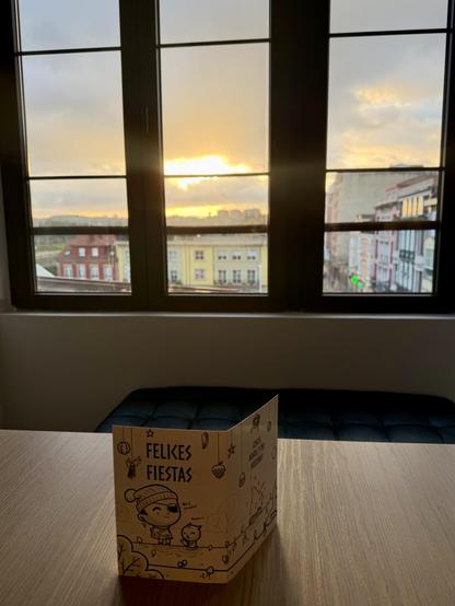 Felicitación de Oneeyedman sobre la mesa del desayuno. Al fondo y tras la ventana, amanece en Avilés. 